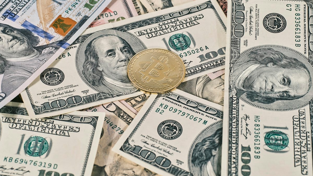 Golden symbolic coin Bitcoin on banknotes of one hundred dollars